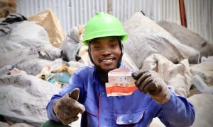 A Karo Enterprise employee holds an empty red and white RUTF sachet, which will be recycled into eco-friendly bricks and paving stones.