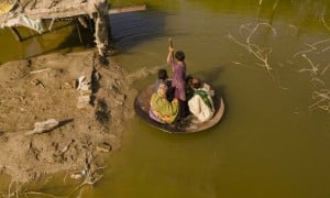 A boy transports people on his curry frying pan across the flooded waters in Jhuddo town of District Mirpurkhas of Sindh, Pakistan, following the devastating floods in 2022.