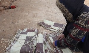 Samira* tears up a worn out-mat to burn amid the harsh winter in Syria