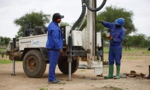Two men with a machine which is boring a hole into the ground
