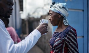 A staff member of the CBCA Virunga Hospital checks a visitor's temperature using a contactless infrared thermometer, before allowing her access to the hospital in Goma, DRC