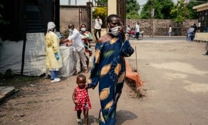 A woman wearing a mask as a preventive measure enters Kyeshero Hospital after passing a checkpoint for hand washing and health screening in Goma