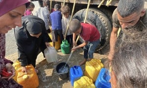 People gather to fill containers with clean water from a tank.
