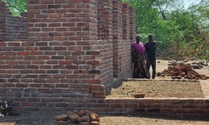John and his wife Mary standing in front of their resilient house under construction. Photo: Concern Worldwide.