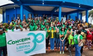 Around 60 people dressed in the green of Concern Worldwide, outside a blue building in Buchanan, LIberia.