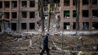 Man walks in front of destroyed building in Ukraine