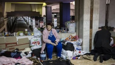 Woman looks sad sitting in Ukraine metro station surrounded by belongings
