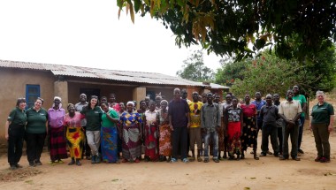 Large group of men and women standing in front of house