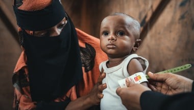 Community health worker assessing infant in Yemen