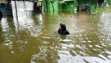 Woman wading through water up to her shoulders in Bangladseh