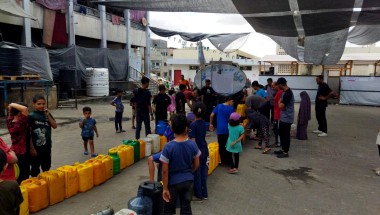 People queuing with water containers at a water truck in North Gaza