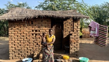 Eliza holds her baby outside her home in Bitilinyu camp