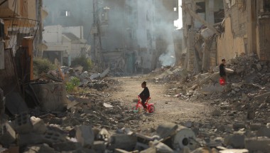 Child on tricycle cycles through destroyed buildings in Gaza