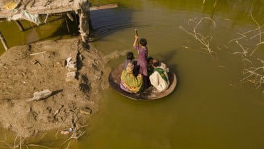 A boy transports people on his curry frying pan across the flooded waters in Jhuddo town of District Mirpurkhas of Sindh, Pakistan, following the devastating floods in 2022.