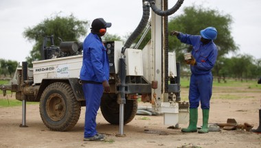Two men with a machine which is boring a hole into the ground
