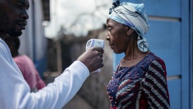 A staff member of the CBCA Virunga Hospital checks a visitor's temperature using a contactless infrared thermometer, before allowing her access to the hospital in Goma, DRC