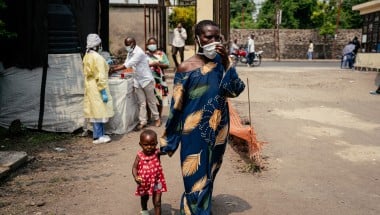 A woman wearing a mask as a preventive measure enters Kyeshero Hospital after passing a checkpoint for hand washing and health screening in Goma