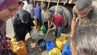 People gather to fill containers with clean water from a tank. 