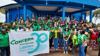 Around 60 people dressed in the green of Concern Worldwide, outside a blue building in Buchanan, LIberia.