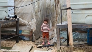A Syrian refugee girl stands next to the water tanks at an informal tented settlement in Akkar, north ofLebanon. Photo taken by Dalia Khamissy/Concern Worldwide.