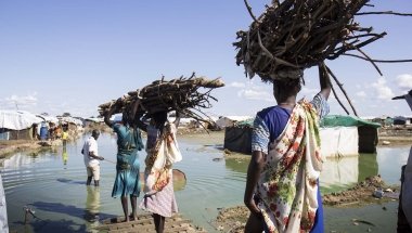 Women carry firewood back to their homes through contaminated flood water in the displacement camp on the UN base in Bentiu. Photo: Concern Worldwide.