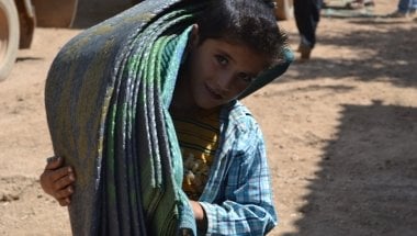 A young boy receives blankets at a Concern distribution at the refugee camp in Turkey. Photo taken by Fionnagh Nally.