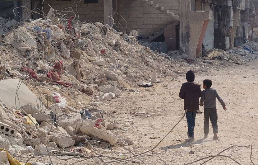 Two children pass by a building totally destroyed by the earthquake in northern Syria