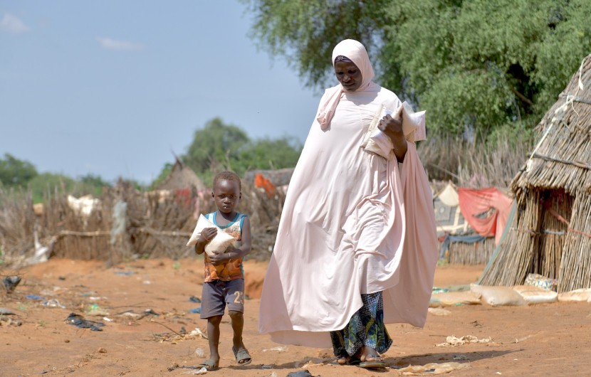 Baria Moumouni carries home packages of fortified flour with her child, distributed by Concern in Tanawara village, Niger. Photo: Concern Worldwide