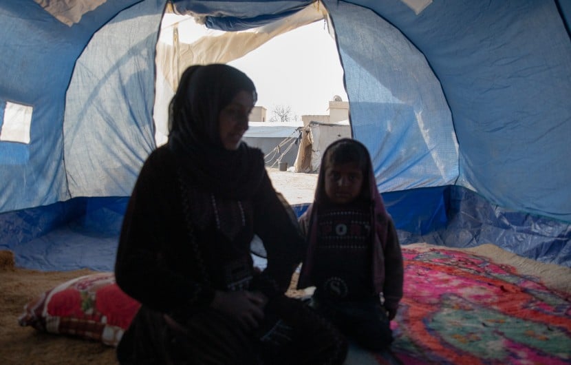 Amira* sits with her youngest child in a tent she calls home, she is one of the 11 million people who have been displaced within Syria during 15 years of conflict. Photo: Gavin Douglas/Concern Worldwide