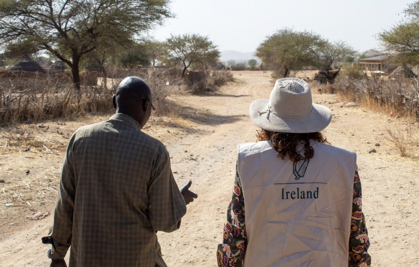 Concern staff member and representative from Irish Embassy to Sudan walk down a sandy road in Sira, Chad