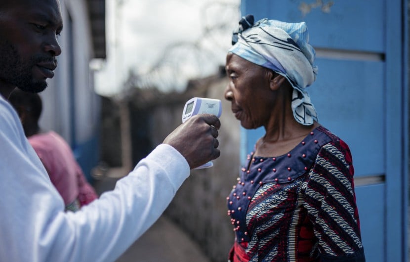 A staff member of the CBCA Virunga Hospital checks a visitor's temperature using a contactless infrared thermometer, before allowing her access to the hospital in Goma, DRC