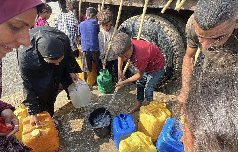 People gather to fill containers with clean water from a tank.