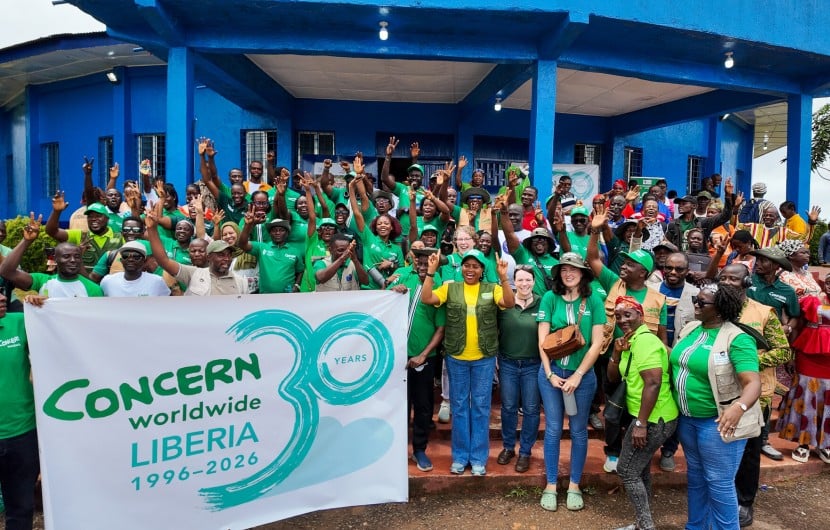 Around 60 people dressed in the green of Concern Worldwide, outside a blue building in Buchanan, LIberia.