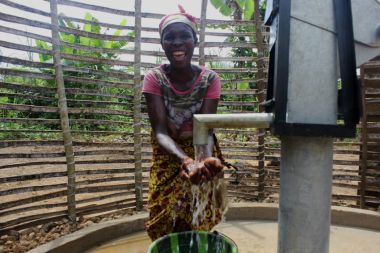 Jatu drinks fresh water at her village well in Liberia.