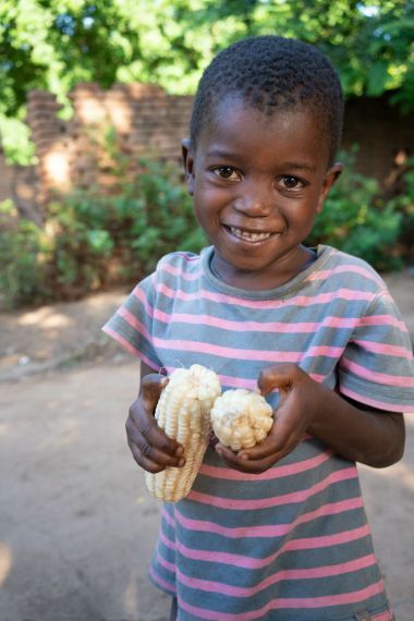 Frank, 4, with some of her family’s juicy corn, fresh from the harvest. Photo: Concern Worldwide.