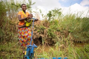Eliza and baby use their new water pump. 