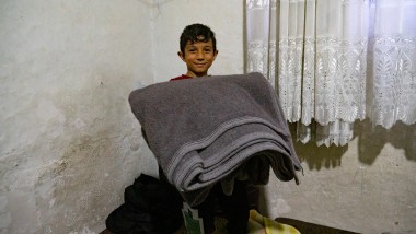 A young boy holds a blanket.