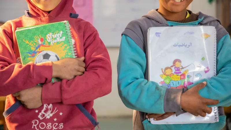 Two children hold up their schoolbooks