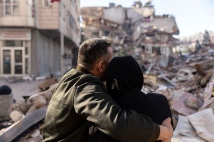 A man and woman embrace as they look at the rubble caused by the earthquakes in Turkey