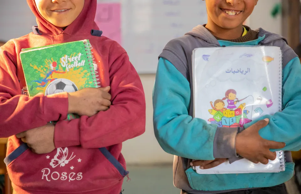 Two children hold up their schoolbooks