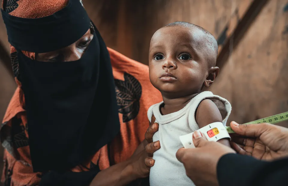 Community health worker assessing infant in Yemen 