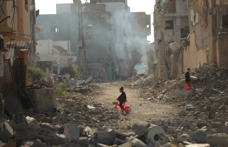 Child on tricycle cycles through destroyed buildings in Gaza