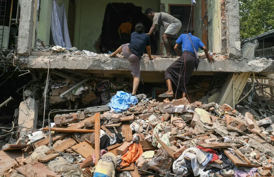 People climb into a damaged building as they look for survivors in Mandalay on March 29, 2025, a day after an earthquake struck central Myanmar. 
