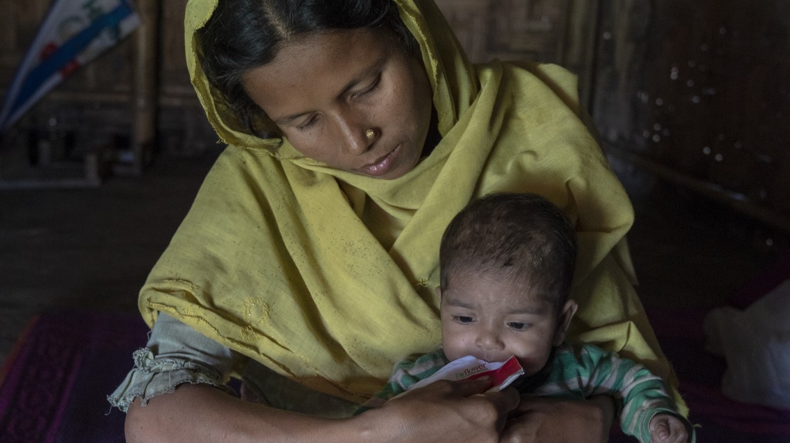Resha gives Tahira a sachet of therapeutic food. The nutrient-rich peanut paste has put Tahira on the road to recovery. Photo: Concern Worldwide.