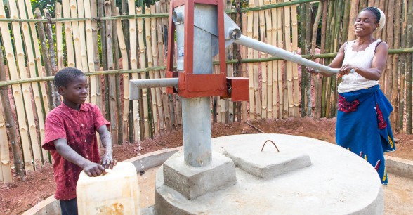 Naomi collects water with her son Lawrence. The village pump was recently installed through a Concern WASH programme. Photo: Gavin Douglas/Concern Worldwide.