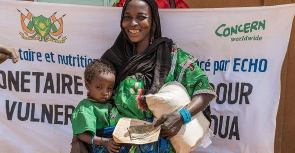 Gaichatou Mohamed receives a distribution of cash and fortified flour from Concern to help meet her basic needs during the lean season. The fortified flour is for her daughter Hadizatou and it contains vital nutrients and vitamins to help keep her well-nourished. Photo: Apsatou Bagaya / Concern Worldwide.
