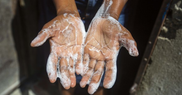 Rosette Mesalien 34 washes her hands with liquid soap she made with help from Concern in front of their home in Cite Soleil slum, a district of Port-au-Prince, Haiti.