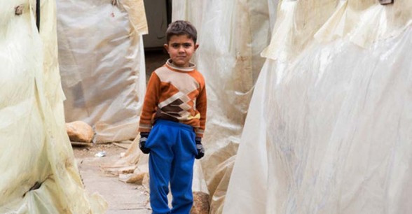A young Syrian refugee stands between the tents at an informal settlement in the north of Lebanon. Photo: Dalia Khamissy / Concern Worldwide.
