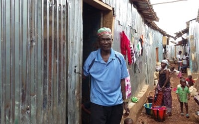 Man stands outside his new home in Kroo Bay.