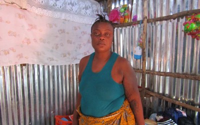 Woman stands in her new home in Kroo Bay